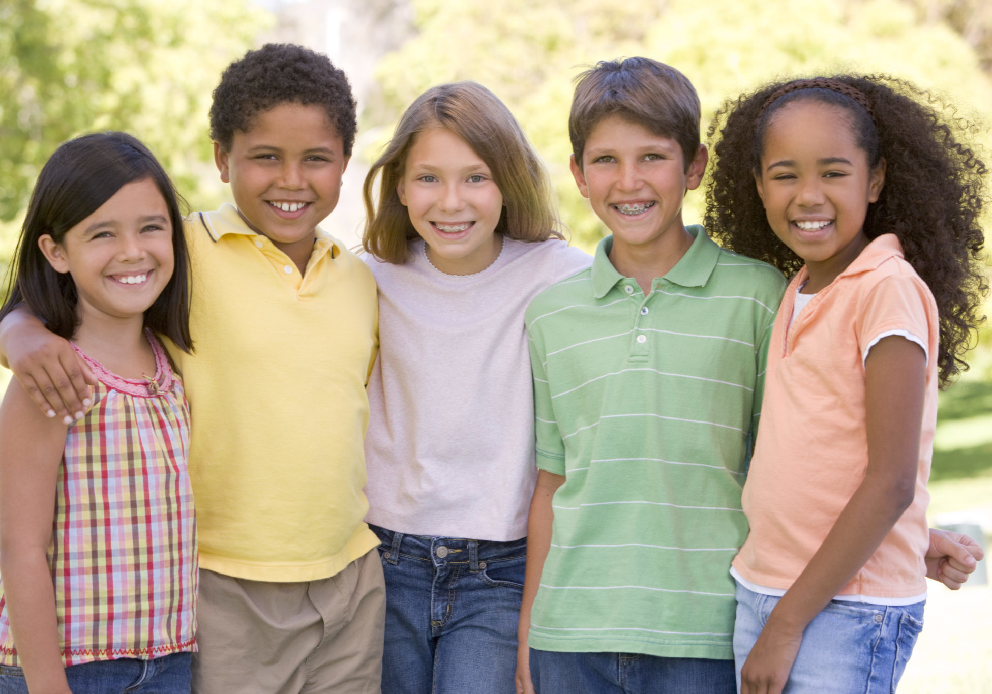 Five young friends standing outdoors smiling